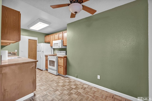kitchen with ceiling fan, a sink, white appliances, light countertops, and baseboards