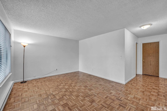empty room featuring baseboards, a textured ceiling, and a baseboard heating unit