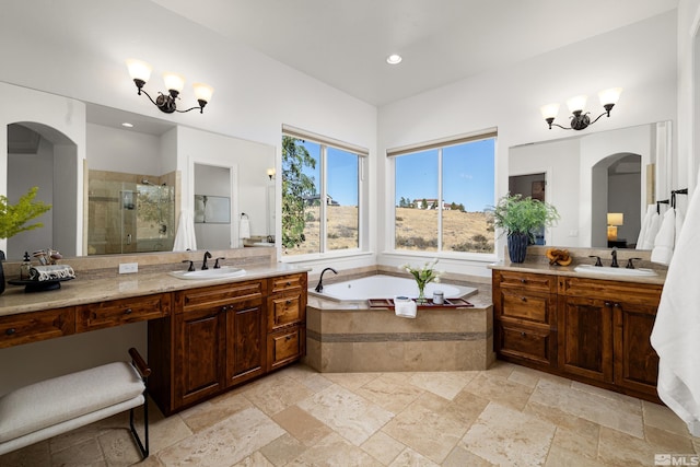 bathroom with a sink, a shower stall, stone tile flooring, and two vanities