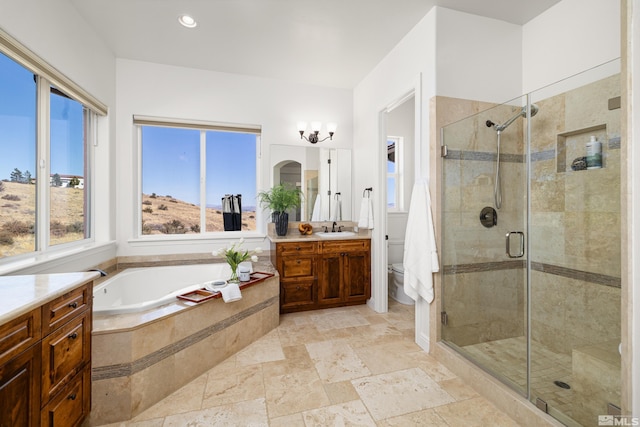 full bath featuring vanity, stone tile floors, toilet, a bath, and a stall shower