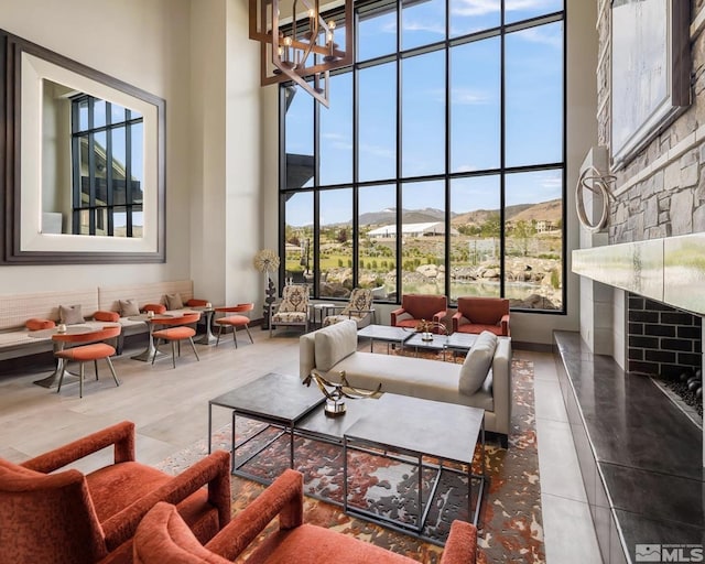 living area featuring a wealth of natural light, a fireplace, a mountain view, and a towering ceiling