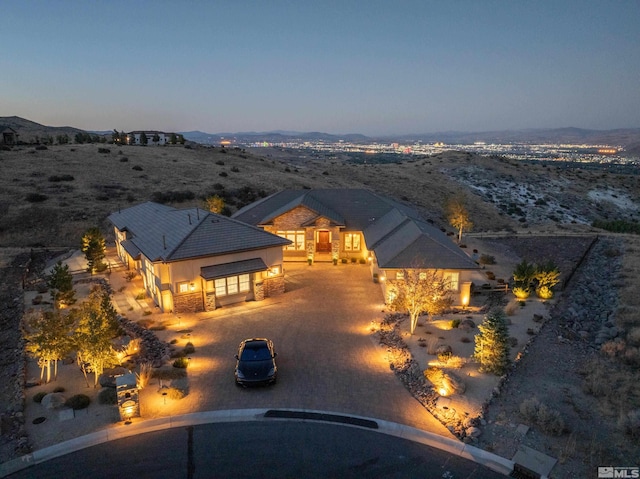 view of front of property featuring driveway, a mountain view, stone siding, and stucco siding