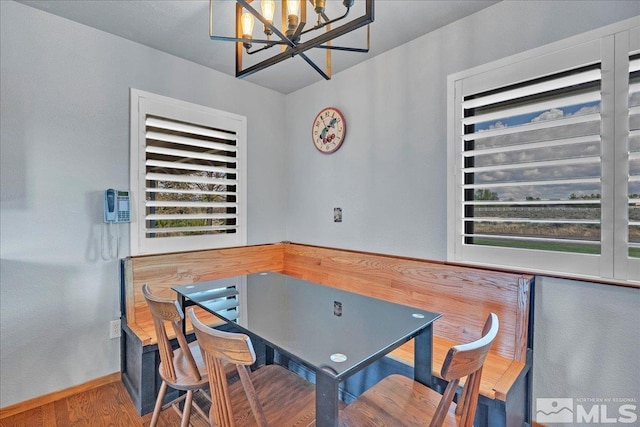 dining space featuring baseboards, wood finished floors, and a chandelier