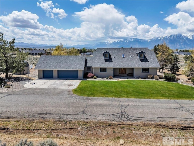 view of front of home featuring driveway, a front yard, a garage, a mountain view, and stucco siding
