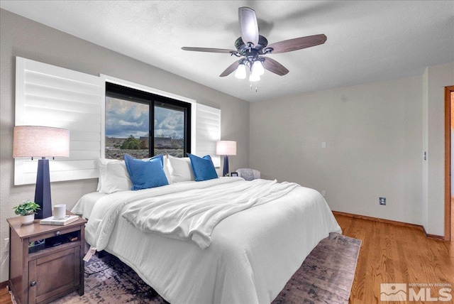 bedroom with baseboards, ceiling fan, and light wood-style flooring