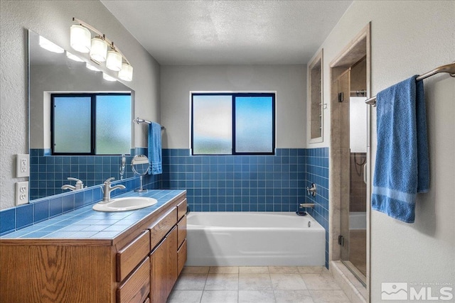 full bathroom with a healthy amount of sunlight, tile patterned floors, vanity, and a stall shower
