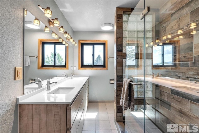bathroom featuring a sink, a textured wall, tile patterned floors, and a shower stall