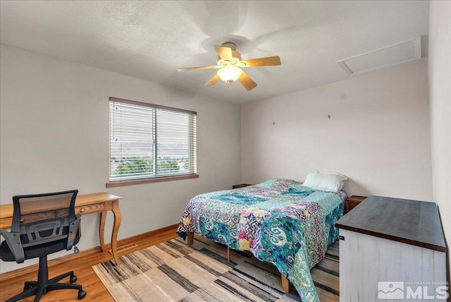 bedroom with baseboards, attic access, a ceiling fan, and wood finished floors