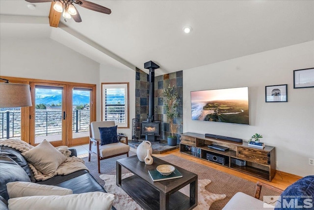 living room with a wood stove, ceiling fan, plenty of natural light, and lofted ceiling