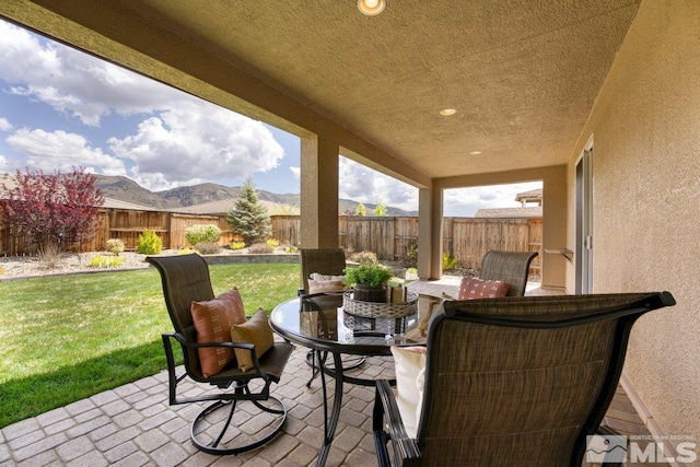 view of patio with a fenced backyard, a mountain view, and outdoor dining area