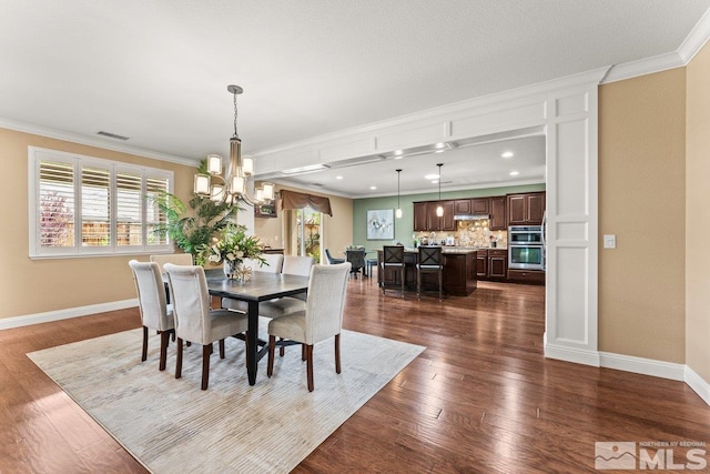 dining room with baseboards, ornamental molding, dark wood finished floors, and a notable chandelier