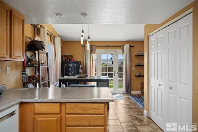 kitchen featuring brown cabinets, light countertops, a peninsula, baseboards, and decorative light fixtures