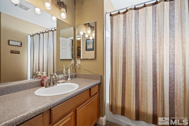 bathroom with vanity, shower / bathtub combination with curtain, and visible vents