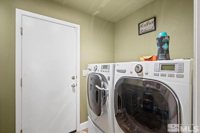 washroom with laundry area, baseboards, and washing machine and dryer