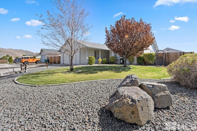 exterior space featuring fence, a mountain view, an attached garage, and a yard