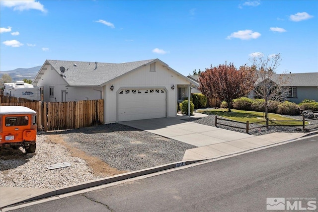 ranch-style home featuring concrete driveway, an attached garage, fence, and a mountain view