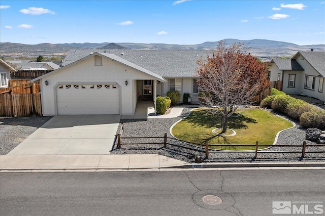 ranch-style house featuring a front lawn, a garage, a mountain view, fence private yard, and driveway