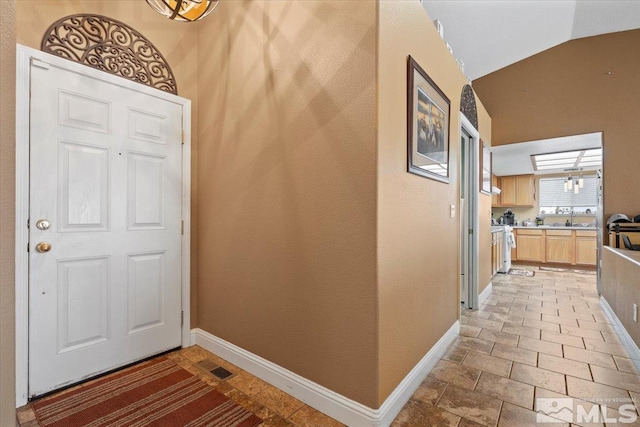 entryway with baseboards, visible vents, and vaulted ceiling