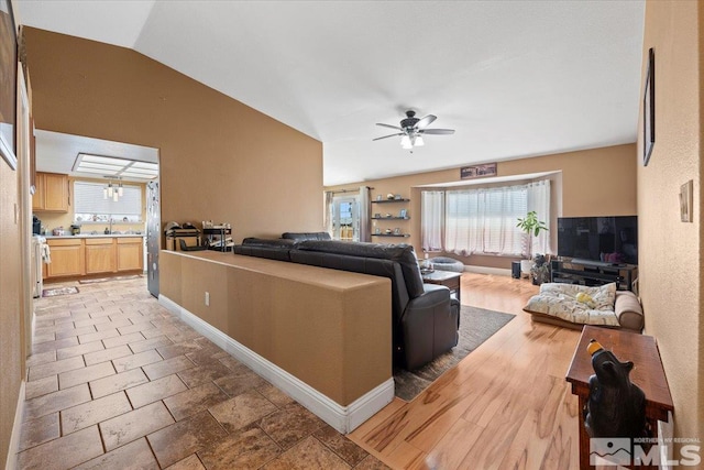 living room with baseboards, ceiling fan, a healthy amount of sunlight, and lofted ceiling