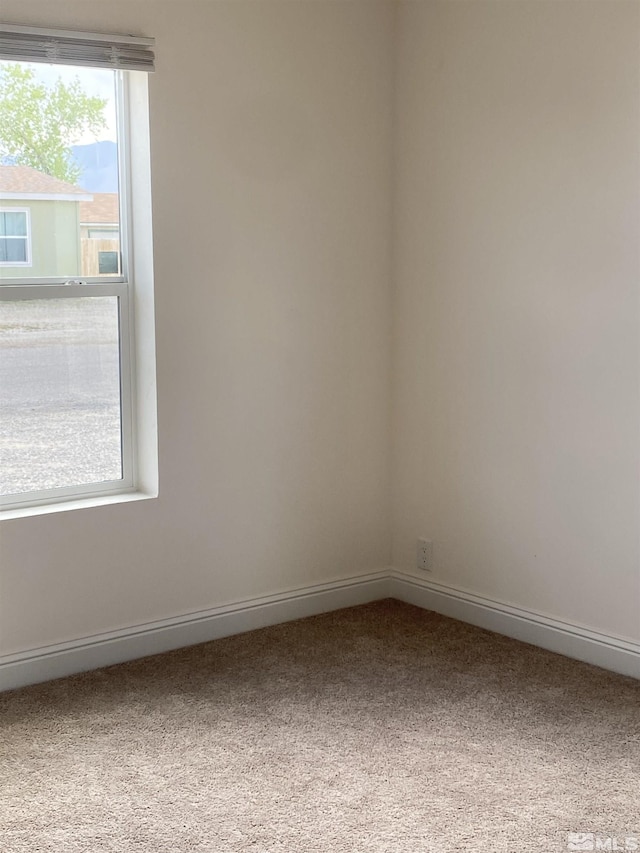carpeted spare room featuring baseboards