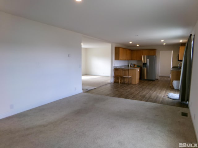 unfurnished living room with carpet floors, baseboards, recessed lighting, and visible vents