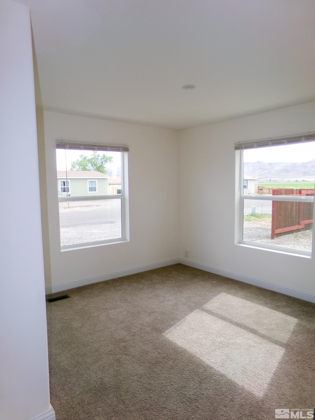 carpeted spare room with baseboards and visible vents