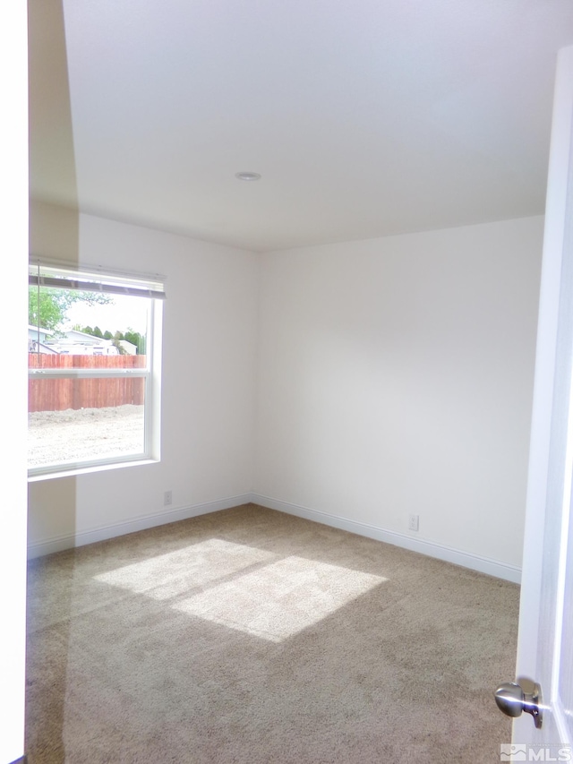 carpeted spare room featuring baseboards