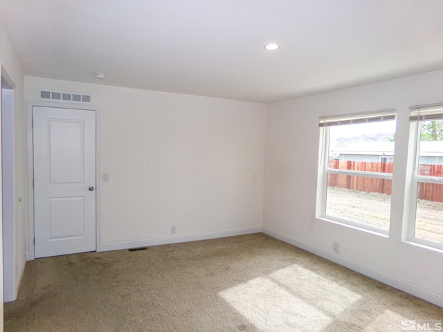 empty room featuring recessed lighting, baseboards, light colored carpet, and visible vents