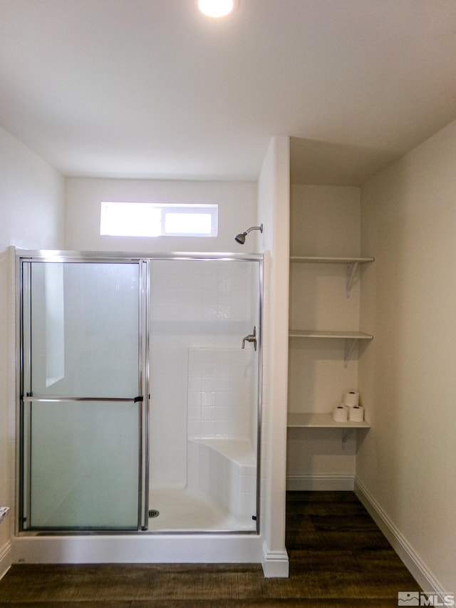 full bathroom with baseboards, wood finished floors, and a shower stall