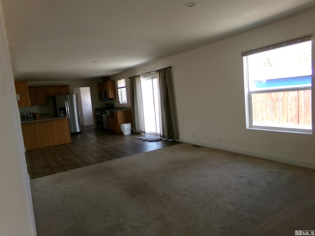 unfurnished living room featuring dark colored carpet, baseboards, dark wood-type flooring, and visible vents
