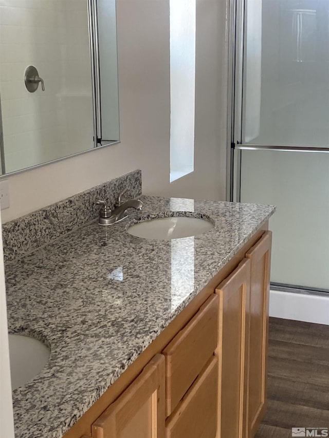 bathroom with an enclosed shower, wood finished floors, and vanity