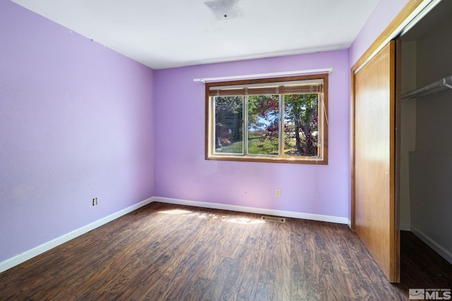 unfurnished bedroom featuring baseboards, wood finished floors, visible vents, and a closet
