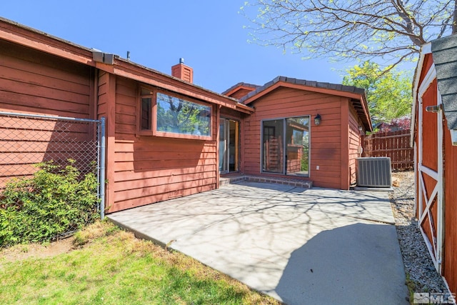 rear view of property with a patio, central AC, fence, and a chimney