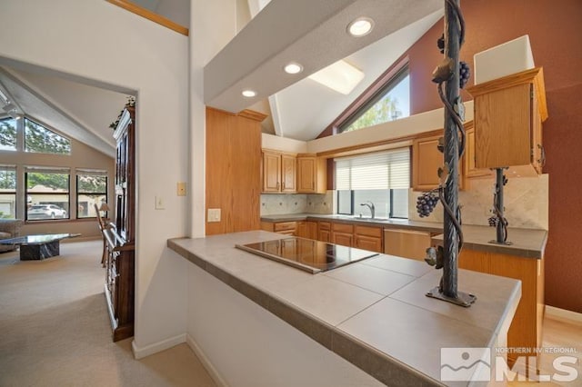 kitchen featuring decorative backsplash, a wealth of natural light, high vaulted ceiling, and black electric cooktop