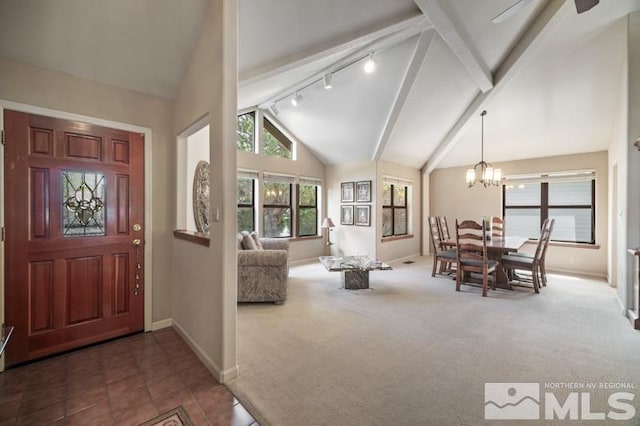 carpeted entrance foyer featuring track lighting, beam ceiling, baseboards, high vaulted ceiling, and a notable chandelier