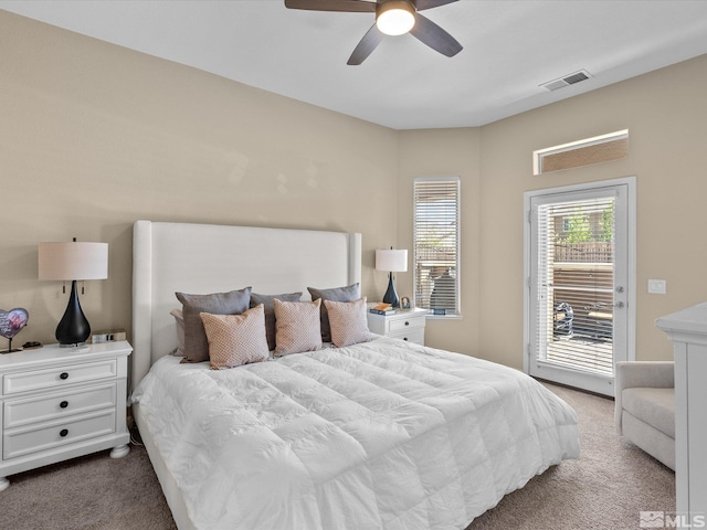 carpeted bedroom with access to outside, a ceiling fan, and visible vents