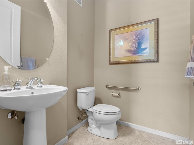 half bathroom featuring toilet, tile patterned floors, and baseboards