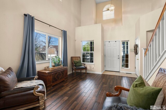 foyer entrance featuring baseboards, wood-type flooring, stairs, and a towering ceiling
