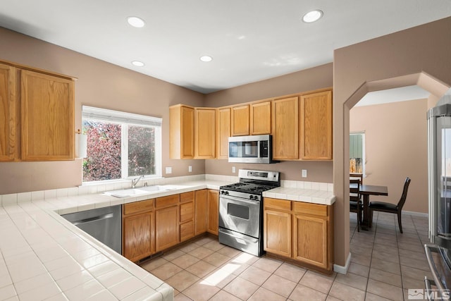 kitchen featuring appliances with stainless steel finishes, a sink, tile counters, recessed lighting, and light tile patterned floors