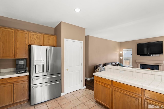 kitchen featuring open floor plan, brown cabinets, light tile patterned flooring, and high quality fridge