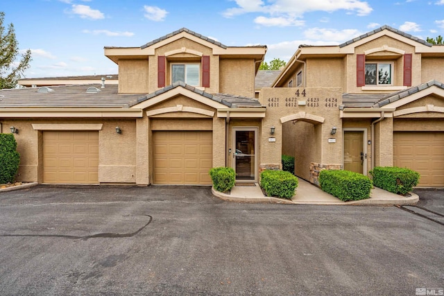 townhome / multi-family property featuring aphalt driveway, stucco siding, and a tile roof
