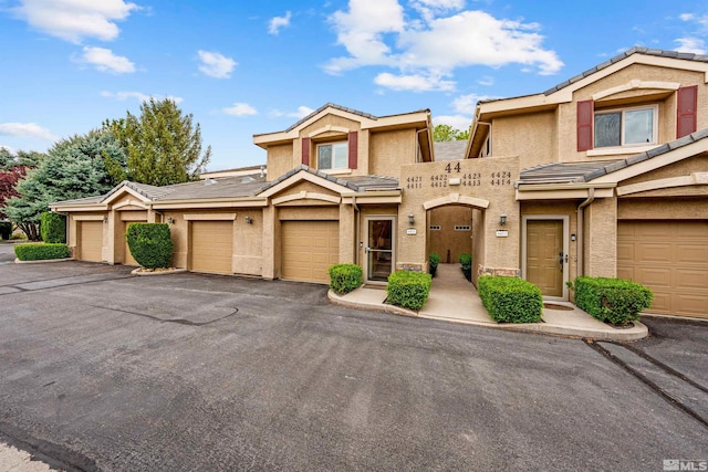 townhome / multi-family property with a tiled roof, community garages, and stucco siding