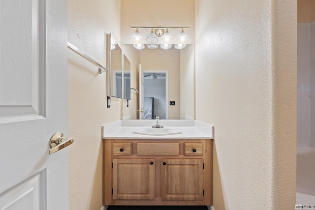 full bath featuring vanity, ceiling fan, and a textured wall