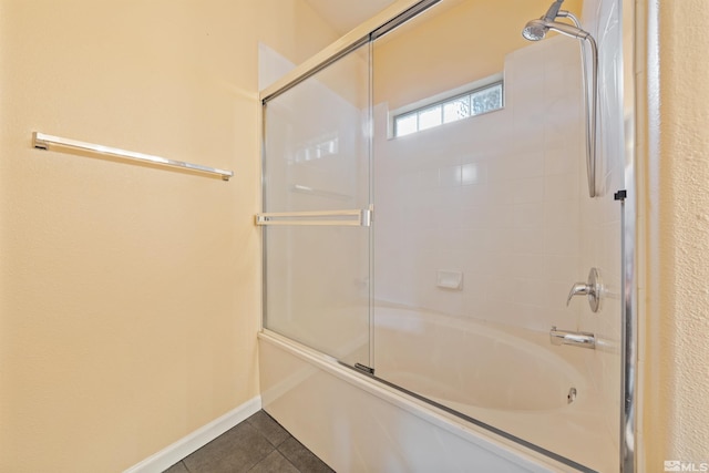 bathroom featuring baseboards, tile patterned flooring, and bath / shower combo with glass door