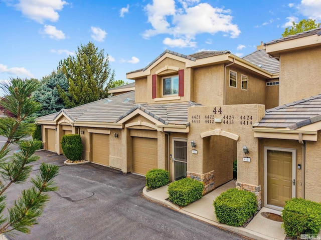multi unit property with a garage, aphalt driveway, stucco siding, and a tile roof