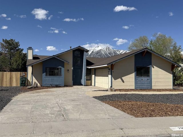 mid-century modern home with an attached garage, fence, driveway, and a chimney