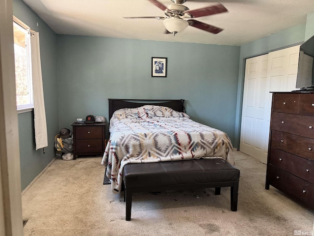 bedroom with a closet, a ceiling fan, and light colored carpet