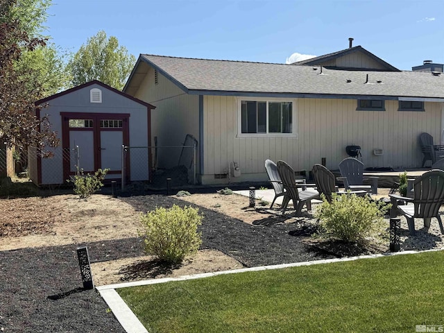 rear view of house with a storage shed, an outbuilding, and roof with shingles