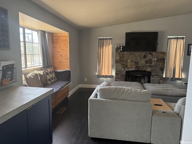 living area featuring baseboards, dark wood-style flooring, and a fireplace