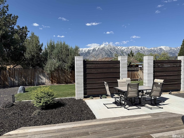 view of patio featuring fence, a mountain view, and outdoor dining area